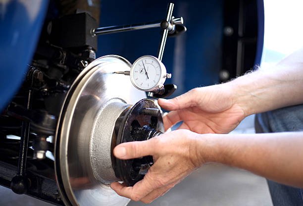 Brake disc run out is being checked by a Mechanic, using a DTI (Dial Test Indicator) gauge, to test to see if they are warped, this can cause brake judder if they are not straight and true.